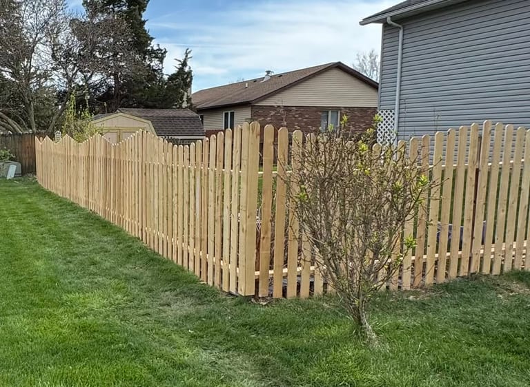 New wood picket fence with a scalloped top rail installed along a residential back yard in the Lafayette, Indiana area by Mercer Precision Construction.