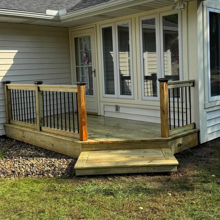Wood deck with an angled corner, black metal balusters and a full-width step, built at the rear of a home by Mercer Precision Construction.